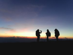 Photo of three people hiking at sunset